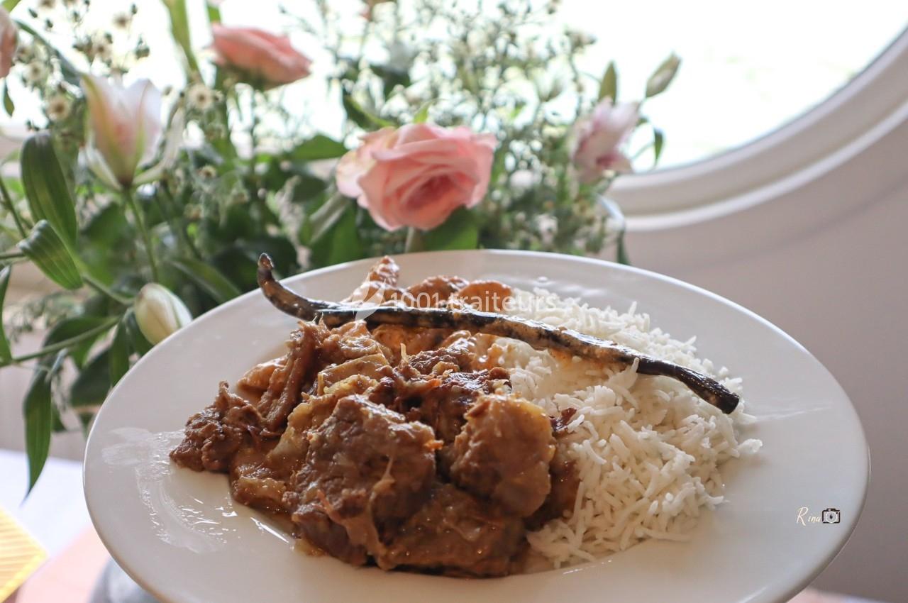Assiette de riz blanc accompagné d'un plat en sauce avec une gousse de vanille, posée devant un bouquet de fleurs.