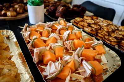 Plateau de charcuterie et fromages avec fruits, légumes, et une bouteille de vin rouge, sur une table en extérieur la nuit.