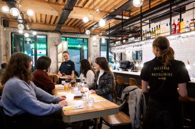 Étagères en bois remplies de produits alimentaires et ménagers dans une petite épicerie lumineuse avec sol carrelé.