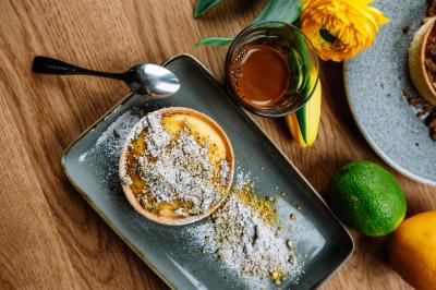 Étagères en bois remplies de produits alimentaires et ménagers dans une petite épicerie lumineuse avec sol carrelé.