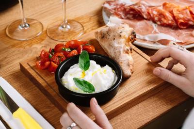 Pizza margherita sortant d'un four à bois avec une façade en mosaïque noire et l'inscription ’N° 900’.