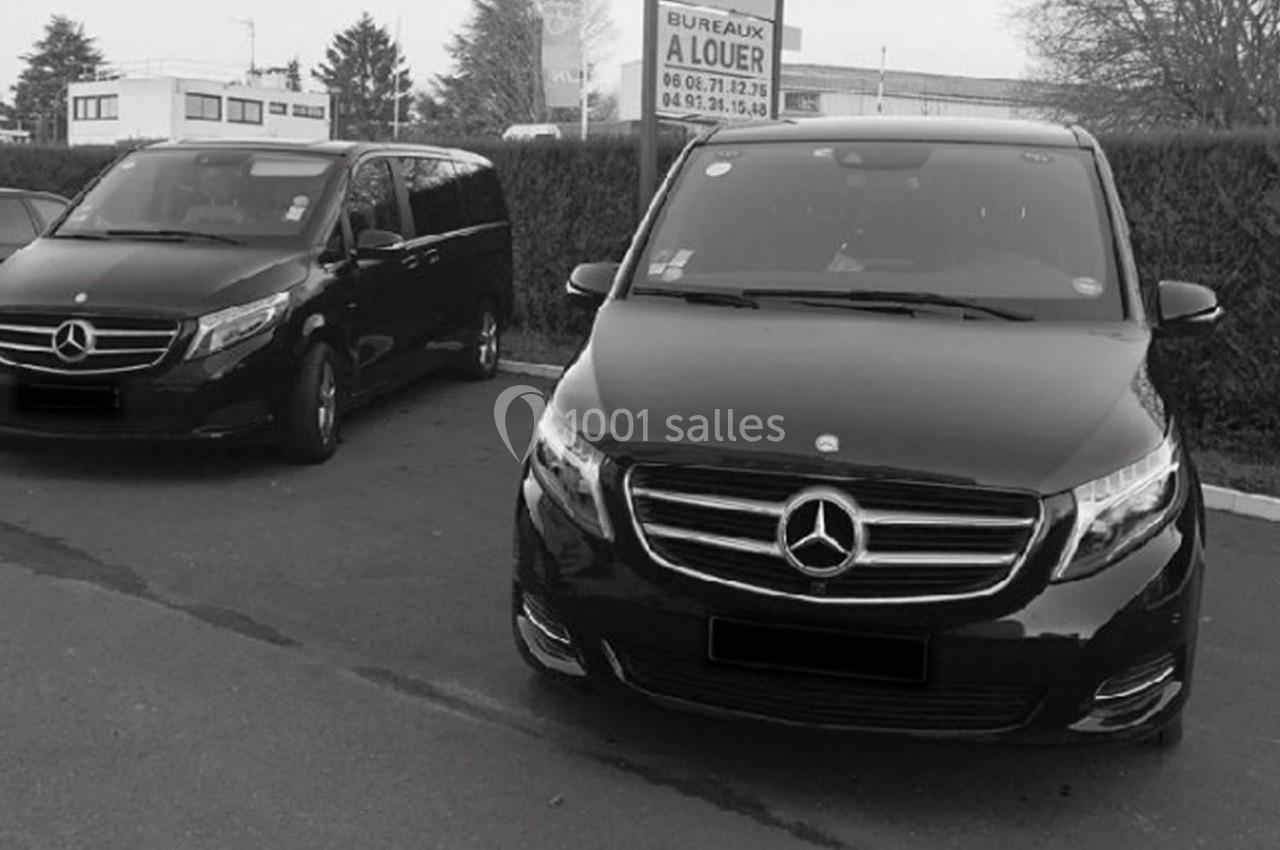 Deux vans noirs Mercedes stationnés sur un parking, avec un panneau ’Bureaux à louer’ en arrière-plan.