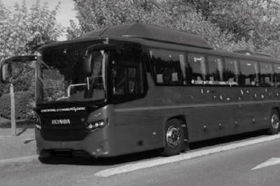 Alignement de véhicules noirs stationnés devant un bâtiment en pierre avec arcades, sous un ciel dégagé.