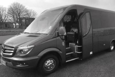 Alignement de véhicules noirs stationnés devant un bâtiment en pierre avec arcades, sous un ciel dégagé.