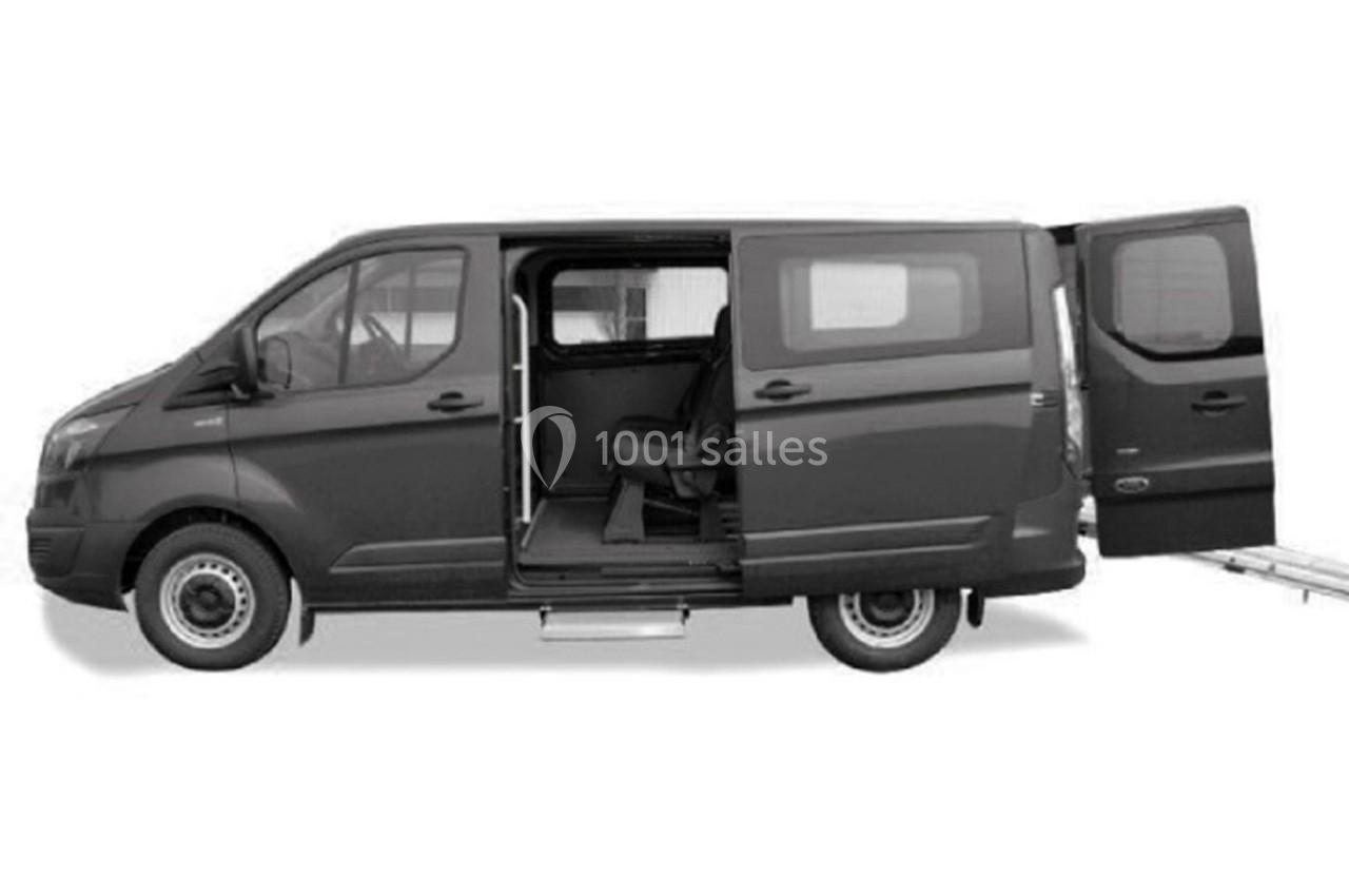 Fourgonnette noire avec portes latérales et arrière ouvertes, équipée d'une rampe d'accès pour fauteuil roulant.