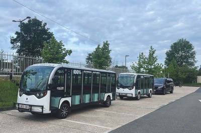 Alignement de véhicules noirs stationnés devant un bâtiment en pierre avec arcades, sous un ciel dégagé.