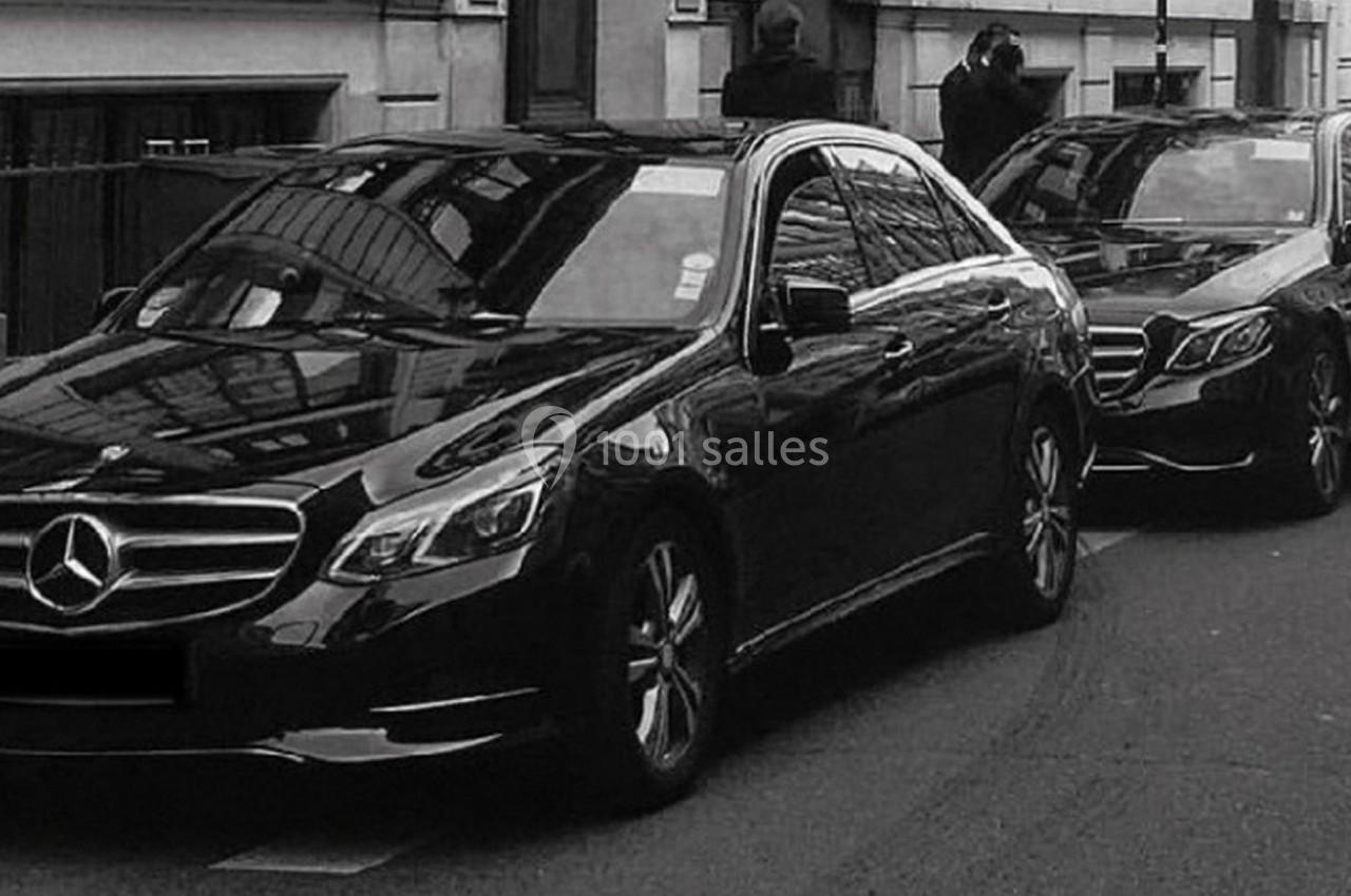 Deux voitures noires de marque Mercedes garées en file sur une rue urbaine.