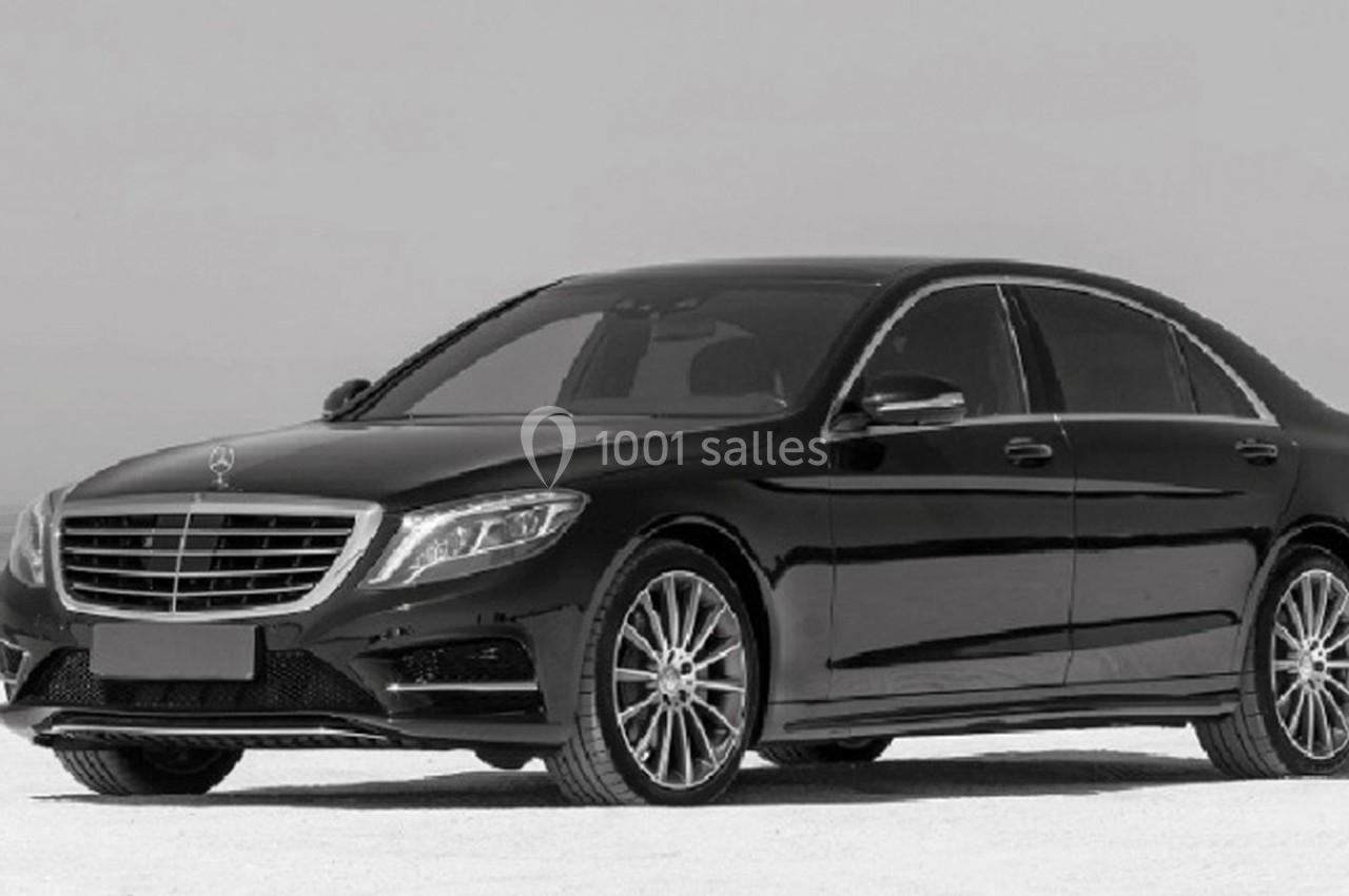 Berline noire stationnée sur une surface claire, photographiée sous un ciel dégagé.