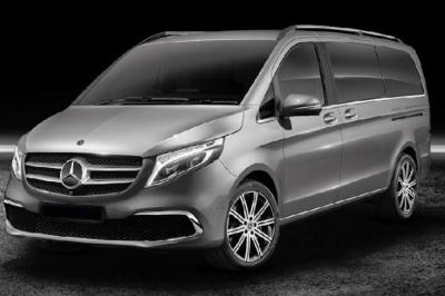 Fourgonnette noire avec portes latérales et arrière ouvertes, montrant un siège accessible et une rampe déployée.