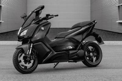 Fourgonnette noire avec portes latérales et arrière ouvertes, montrant un siège accessible et une rampe déployée.