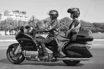 Fourgonnette noire avec portes latérales et arrière ouvertes, montrant un siège accessible et une rampe déployée.