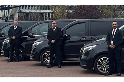 Fourgonnette noire avec portes latérales et arrière ouvertes, montrant un siège accessible et une rampe déployée.