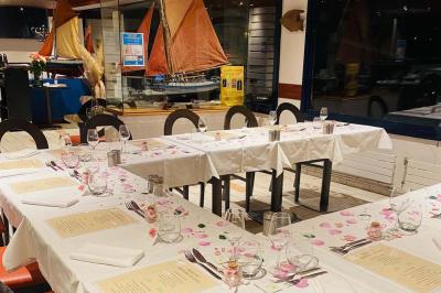 Deux cocktails colorés et une assiette d'olives sur une table en bois, avec un coucher de soleil en arrière-plan.