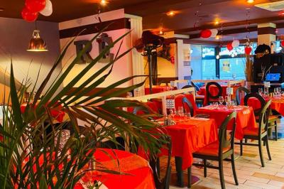 Deux cocktails colorés et une assiette d'olives sur une table en bois, avec un coucher de soleil en arrière-plan.