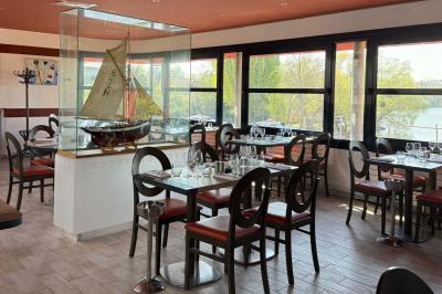 Deux cocktails colorés et une assiette d'olives sur une table en bois, avec un coucher de soleil en arrière-plan.