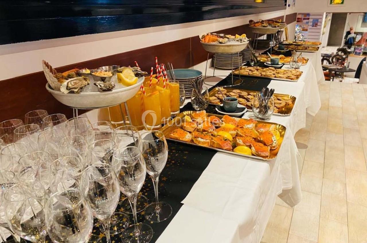 Buffet varié avec fruits de mer, verrines, jus et coupes en verre sur une table dressée.