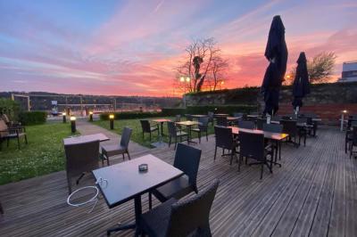 Deux cocktails colorés et une assiette d'olives sur une table en bois, avec un coucher de soleil en arrière-plan.