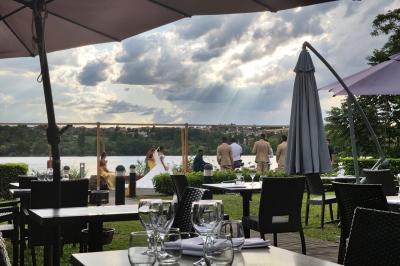 Deux cocktails colorés et une assiette d'olives sur une table en bois, avec un coucher de soleil en arrière-plan.