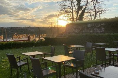 Deux cocktails colorés et une assiette d'olives sur une table en bois, avec un coucher de soleil en arrière-plan.