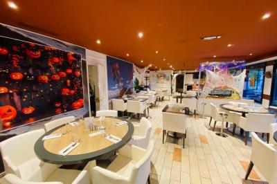 Deux cocktails colorés et une assiette d'olives sur une table en bois, avec un coucher de soleil en arrière-plan.