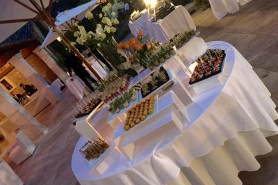 Buffet élégant en extérieur avec tables rondes garnies de verrines, fleurs et amuse-bouches sous des parasols.