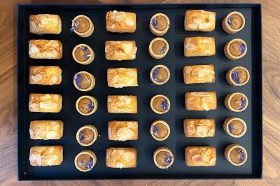 Sandwiches colorés empilés avec des garnitures variées, entourés de roquette et d'olives vertes.