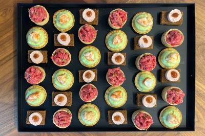 Sandwiches colorés empilés avec des garnitures variées, entourés de roquette et d'olives vertes.