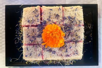 Sandwiches colorés empilés avec des garnitures variées, entourés de roquette et d'olives vertes.