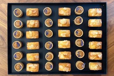 Sandwiches colorés empilés avec des garnitures variées, entourés de roquette et d'olives vertes.