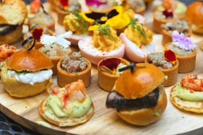 Sandwiches colorés empilés avec des garnitures variées, entourés de roquette et d'olives vertes.