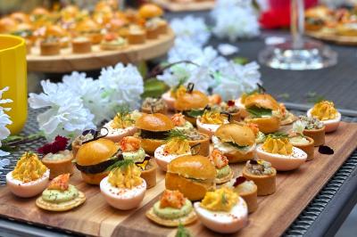 Sandwiches colorés empilés avec des garnitures variées, entourés de roquette et d'olives vertes.