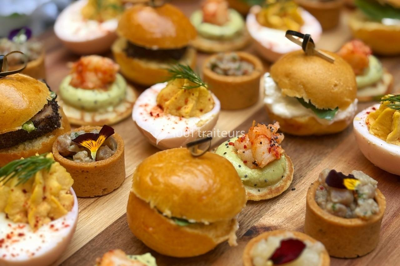 Assortiment de bouchées apéritives variées, incluant mini-burgers, tartelettes et garnitures raffinées.