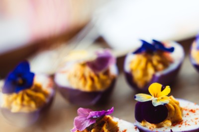 Plateau de canapés variés disposés sur une table en bois, décorée de fleurs et de bougies.