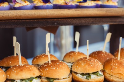 Plateau de canapés variés disposés sur une table en bois, décorée de fleurs et de bougies.