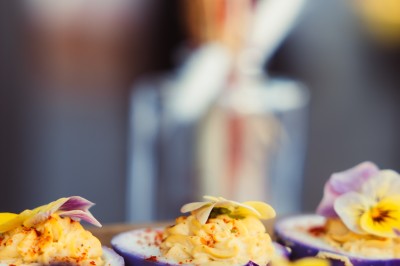 Plateau de canapés variés disposés sur une table en bois, décorée de fleurs et de bougies.