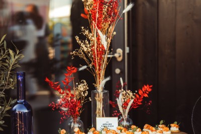 Plateau de canapés variés disposés sur une table en bois, décorée de fleurs et de bougies.