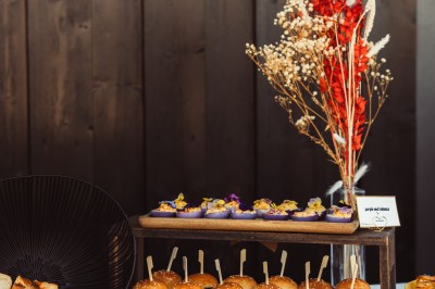 Plateau de canapés variés disposés sur une table en bois, décorée de fleurs et de bougies.