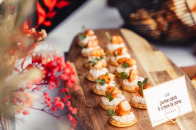 Plateau de canapés variés disposés sur une table en bois, décorée de fleurs et de bougies.