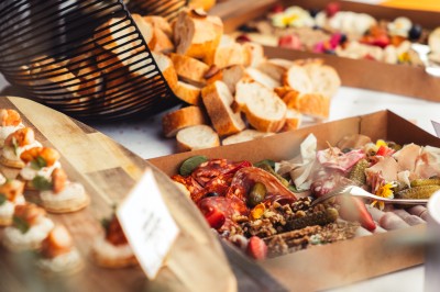 Plateau de canapés variés disposés sur une table en bois, décorée de fleurs et de bougies.