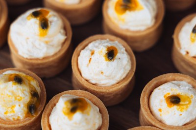 Plateau de canapés variés disposés sur une table en bois, décorée de fleurs et de bougies.