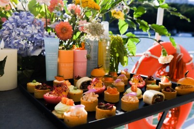 Plateau de canapés variés disposés sur une table en bois, décorée de fleurs et de bougies.