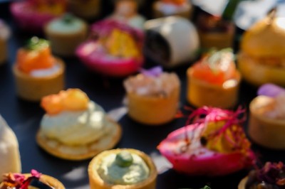 Plateau de canapés variés disposés sur une table en bois, décorée de fleurs et de bougies.