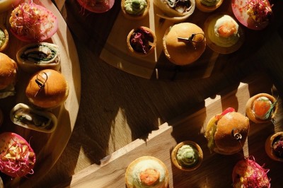 Plateau de canapés variés disposés sur une table en bois, décorée de fleurs et de bougies.