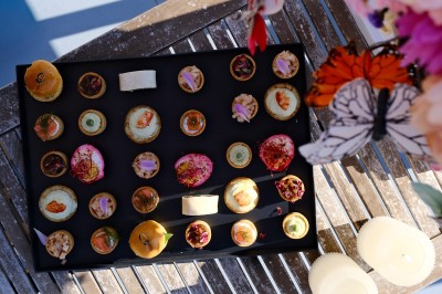 Plateau de canapés variés disposés sur une table en bois, décorée de fleurs et de bougies.