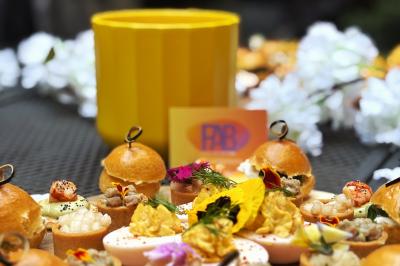 Plateau de bouchées apéritives variées avec fleurs comestibles, présenté sur une table avec un pot jaune en arrière-plan.