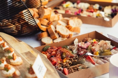 Buffet avec planches de charcuterie, pains, canapés et légumes, présenté sur une table en extérieur.