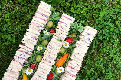 Sandwiches colorés empilés avec des garnitures variées, entourés de roquette et d'olives vertes.