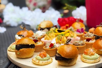 Sandwiches colorés empilés avec des garnitures variées, entourés de roquette et d'olives vertes.