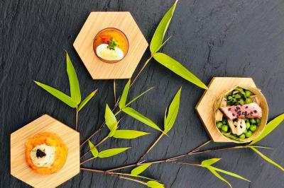 Assortiment de plats gastronomiques présentés sur des assiettes hexagonales en bois, décorés de feuilles de bambou.