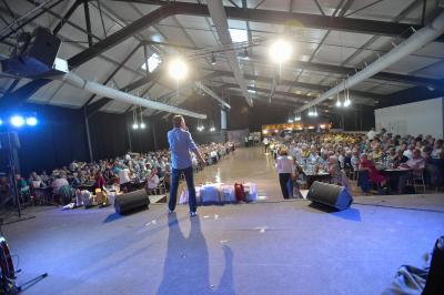 Vue aérienne d'un bâtiment avec un toit rouge entouré de forêt, d'une route et d'un petit cours d'eau.